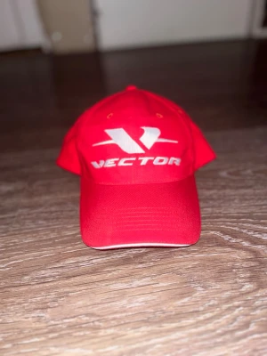 Röd keps från CCM med Vector-logga - Snygg röd keps från CCM med stor vit Vector-logga broderad framtill. Klassisk böjd skärm och justerbar passform. Tillverkad i slitstarkt tyg och har ventilerande hål upptill. Perfekt accessoar för en sportig look.