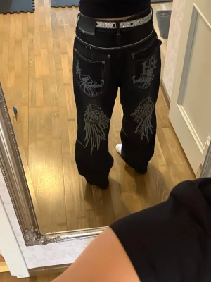 Svarta baggy jeans med brodyr - Säljer ett par svarta baggy jeans med vita kontrastsömmar och brodyr detaljer. Köpte på second hand och vet inte vilket märke det är men säljer för att dom är för stora. 