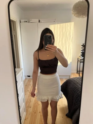 Mörkbrun croppad linnetopp - Snygg mörkbrun croppad linnetopp med tunna axelband och enkel, stilren design. Om ni är intresserade i kjolen finns de i ett annat inlägg!😁Toppen har en lätt glansig finish och sitter tight mot kroppen, perfekt för att matcha med kjol eller jeans.🤩