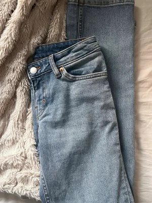 Ljusblå raka jeans ifrån Monki - Säljer ett par ljusblå jeans med klassisk femficksmodell och raka ben. Jeansen har låg midja och snygga kontrastsömmar. Perfekta för en avslappnad och trendig look. Materialet är denim i bomull och de har metallknapp och dragkedja.
