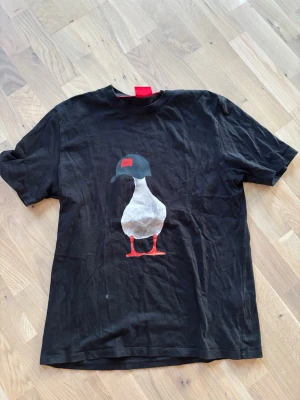 Svart t-shirt från HUGO - Svart t-shirt från HUGO med en stor tryckt anka på framsidan. Väldigt häftig och har knappt snvändit bara legat i lådan. Skriv om ni har frågor!!! Pris ej hugget i sten.