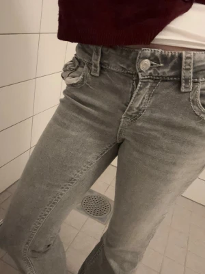 Grå jeans från Gina Tricot - Säljer ett par grå jeans från Gina Tricot med raka ben och klassisk femficksmodell. Jeansen har dragkedjegylf, bälteshällor och snygga slitningar vid knäna. Perfekta för en avslappnad och trendig look. Low bootcut. Säljer då de är för små strl 158❤️❤️