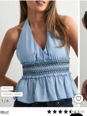 Ljusblå halterneck topp från Nelly - Snygg ljusblå halterneck topp från Nelly med smockad midja och volang nedtill. Toppen knyts i nacken och har öppen rygg, vilket ger en fräsch och somrig look. Perfekt till jeans eller kjol för en trendig stil. säljer pågrund av att den var för stor och satt inte så bra på mig och den är aldrig använd, prislappen sitter kvar!!💘💘