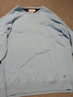 Ljusblå sweatshirt från Cool Blue - Ljusblå sweatshirt från Cool Blue by Berns Brands. Tröjan har rund halsringning och ribbade muddar vid ärmslut och nederkant. Enkel och stilren design utan tryck eller mönster, perfekt för en avslappnad look.