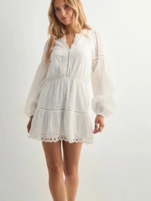 Vit kort klänning med spetsdetaljer - Lappen är kvar! Helt ny! Söt vit kortklänning med broderade spetsdetaljer och v-ringning. Klänningen har långa, lätt puffade ärmar och volangkant nedtill. Tillverkad i luftig bomull, perfekt för varma dagar. Ger en romantisk och trendig look.