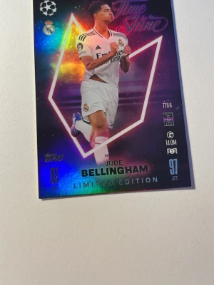 Limited Edition fotbollssamlarkort - Säljer ett Limited Edition fotbollssamlarkort med holografisk yta och motiv av en spelare i Real Madrid-dräkt. Kortet har färgstarka detaljer i blått, lila och rosa samt text och symboler relaterade till Champions League.