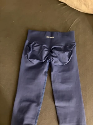 DFYNE Seamless Scrunch Leggings - Mörkblå - Storlek XS - Beskrivning: Säljer mina mörkblå (dark navy) DFYNE seamless leggings. De är i storlek Extra Small (XS) och är de ultimata gymtightsen för dig som vill ha både stil och funktion! Tightsen har den välkända scrunch butt-detaljen (som syns tydligt på bild 1 och 4) som ger en fantastiskt form. Materialet är squat-proof, stretchigt och har en bekväm hög midja som sitter på plats. De är i mycket fint skick och säljes då jag rensar ut min samling. Passa på att knipa ett par riktiga favoriter! 