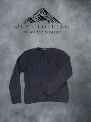 Mörkblå kabelstickad tröja Polo Ralph Lauren - Väldigt fint skick med få användningar. Kabelstickad mörkblå tröja från Polo Ralph Lauren med rund halsringning och den klassiska röda logotypen broderad på bröstet. Tröjan har ribbade muddar vid ärmslut och nederkant. (nypris 2099) 