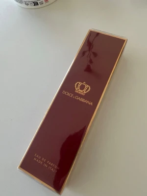 Dolce & Gabbana Eau de Parfum - Lyxig parfym från Dolce & Gabbana i en elegant mörkröd och guld box. Doften har inslag av citron, körsbär och cederträ. Förpackningen är av kartong med guldfärgade detaljer och kron-symbol. Tillverkad i Italien.