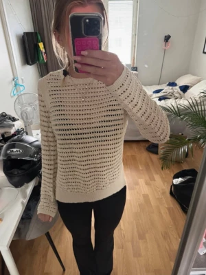 Beige stickad tröja med hålmönster - Säljer en beige stickad tröja med hålmönster och rund hals. Tröjan är långärmad och har ribbade muddar vid ärmslut och nederkant. Perfekt för lager-på-lager och enkel att matcha med olika outfits.