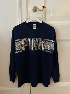 Mörkblå långärmad topp från PINK - Säljer en mörkblå, långärmad topp med glittrig text där det står PINK från PINK i storlek S. Oversized passform. Väldigt bra skick! 💙💙