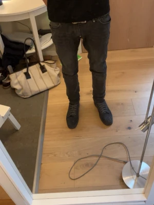 Gråa loubs - Snygga svarta sneakers med klassisk låg profil och röd sula. Skorna har en stilren design med svarta skosnören och diskreta detaljer. Perfekta för dig som gillar en clean look med en twist. Passar till både jeans och andra streetwear-outfits.