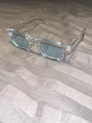 Transparenta rektangulära solglasögon - Snygga solglasögon med transparent plastbåge och rektangulära gråtonade linser. Perfekt för dig som vill ha en modern och stilren look. Bågarna är lätta och har en cool, minimalistisk design som passar till många outfits.
