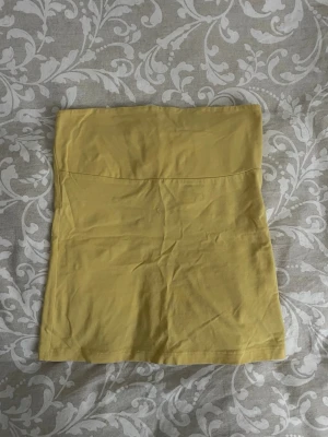 Gul tubtopp från Gina Tricot - Snygg gul tubtopp från Gina Tricot i mjuk bomull. Enkel och stilren design utan axelband, perfekt att matcha med jeans eller kjol. Toppen har en bandeauformad passning.