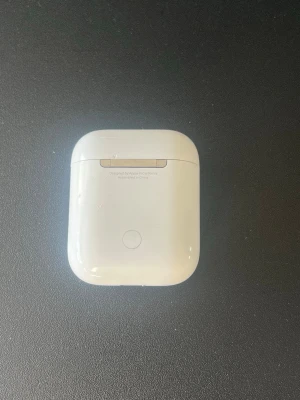 Apple AirPods med laddningsetui - Säljer ett par trådlösa Apple AirPods med vitt laddningsetui. Klassisk stilren design i blank vit plast, perfekt för dig som vill ha smidiga hörlurar till mobilen. AirPods är lätta och har en ikonisk form som sitter bekvämt i öronen. Laddare följer med!