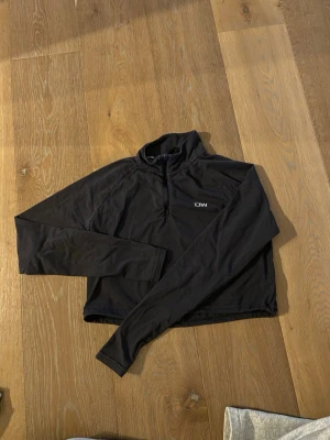 Grå långärmad träningströja ICANIWILL - Grå långärmad träningströja från ICANIWILL med halv dragkedja framtill och hög krage. Tillverkad i ett stretchigt och mjukt funktionsmaterial som passar perfekt till gymmet eller löprundan. Diskret logga på bröstet.