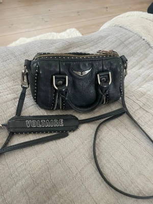 Svart handväska Zadig & Voltaire - Cool svart handväska från Zadig & Voltaire i läder med silverfärgade detaljer och nitar. 🆕 Nypris Sunny Nano Studs Bag i svart läder med nitar: 4000 kr  📍Använd: Sprucket skinn och rostande metalldetaljer (syns på bilder)