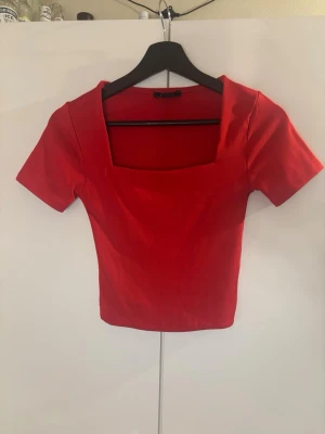 Röd crop top med fyrkantig urringning - En röd crop top från New yorker med korta ärmar och en trendig fyrkantig urringning. Toppen är figurnära och gjord i ett stretchigt material som sitter bekvämt. Perfekt att matcha med höga jeans eller kjol💕