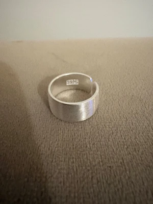 Handgjord ring i äkta Sterling Silver 925 - Borstad, Wide cuff - Justerbar  - Tidlös ring i äkta Sterling Silver 925, handgjord - med borstad finish.   Den breda designen ger ett stilrent och kraftfullt uttryck – perfekt både till vardags och fest.    - Material: Äkta Sterling Silver (925-silverstämpel)   - Design: Handgjord, Borstad yta, Wide cuff - Passar: Kvinna – justerbar/bekväm passform   - Skick: Helt ny   - Frakt: Alltid snabb leverans   💫  Se även mina övriga annonser för fler stilrena silverringar. Mängdrabatt tillämpas 💫
