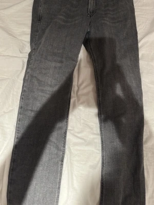 Grå jeans från Diesel - Snygga grå jeans från Diesel med klassisk femficksdesign och diskret logga på myntfickan. Jeansen har raka ben och är tillverkade i ett mjukt denimtyg som ger en avslappnad vibe. Perfekta för dig som gillar en stilren och tidlös look.