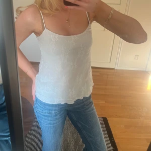 Vit spetslinnetopp med tunna band - Säljer en söt vit linnetopp med tunna axelband som går att justera och blommig spetsdetalj. Toppen har en rak passform och har tre olika lager som gör den extra fin (se bild 4) 😊😊
