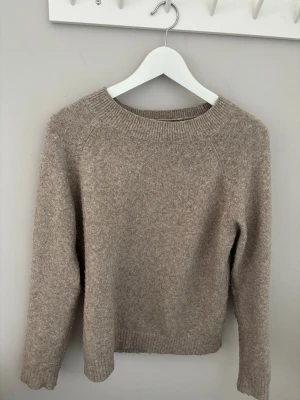Beige stickad tröja - Mysig beige stickad tröja med rund hals och långa ärmar. Tröjan är lite nopprig.   Materialet är mjukt och värmande.