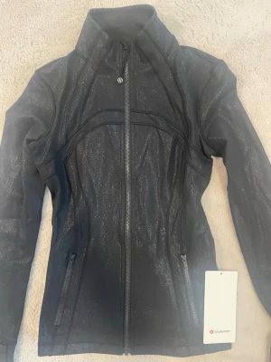  Lululemon define jacka - Jätte snygg och ovanlig svart glittrig jacka från Lululemon säljer pga inte kommit till användning så den är i perfekt skick utan minsta defekt. Kostar igentligen 1300kr