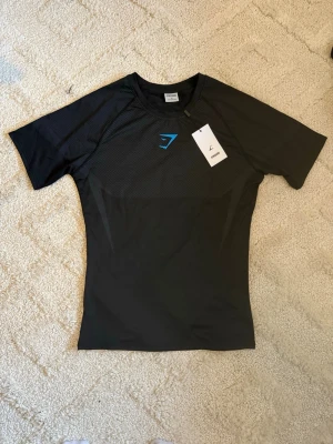 Gymshark Onyx V5 Tröja – Svart & Blå - Gymshark Onyx V5 Tröja – Svart & Blå 👕 Storlek: M 🎨 Färg: Svart med blå detaljer ✨ Skick: Nyskick – endast testad 🧵 Modell: Onyx V5
