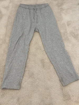 Grå mjukisbyxor  - Ett par klassiska grå mjukisbyxor. Byxorna har raka ben och är tillverkade i mjukt, stretchigt material som känns skönt mot huden. Perfekta för chill dagar hemma eller när du vill ha det bekvämt.