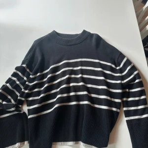 Svartvit randig stickad tröja Gina Tricot - Snygg svart stickad tröja från Gina Tricot i storlek S med vita horisontella ränder. Tröjan har rund hals, ribbade muddar och är långärmad. Perfekt för dig som gillar klassisk stil med en modern twist.