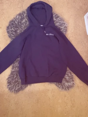 Mörkblå hoodie med tryck 'Ma Chérie' - Snygg mörkblå hoodie med huva och trycket 'Ma Chérie' i vitt på bröstet och ryggen. På ryggen finns även två hjärtan som detalj. Hoodien har långa ärmar och ribbade muddar vid ärmslut och nederkant. Perfekt för en chill och trendig look.