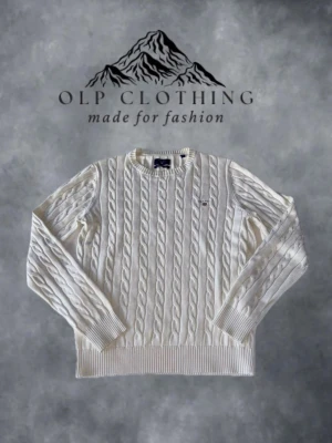 Vit kabelstickad tröja från GANT - Kabelstickad vit tröja från GANT med rund halsringning och ribbade muddar. Tröjan har GANT:s klassiska logga broderad på bröstet och är tillverkad i mjukt material som ger en clean och tidlös look. Tröjan är nästan aldrig använd och i riktigt bra skick. Bilderna visar en person som är 175 cm lång och när storlek S.