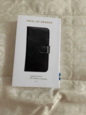 Svart wallet mobilskal iDeal of Sweden - Snyggt svart wallet mobilskal från iDeal of Sweden. Skal i plånboksmodell med magnetstängning och plats för kort. Passar till iPhone 12 Pro Max. Tillverkat i konstläder med stilren design.