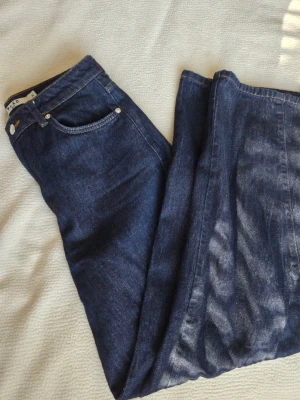Mörkblå jeans från NAKD - Snygga mörkblå jeans från NAKD i modellen wide leg jean med klassisk femficksdesign och kontrastsömmar. Jeansen har raka ben och är tillverkade i slitstarkt denim-material. Perfekta för dig som gillar en tidlös och enkel look.