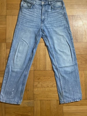 Ljusblå Loose-Fit Jeans - Säljer ett par ljusblå jeans med rak passform och klassisk femficksdesign. Jeansen har hög midja och är tillverkade i denim med snygg tvättad look. Perfekta för en avslappnad och trendig stil.