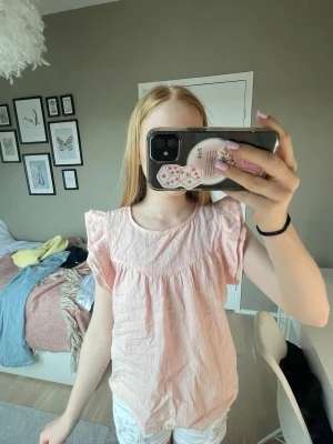 Ljusrosa blus med volangärmar - Söt ljusrosa blus med korta volangärmar och rund halsringning. 