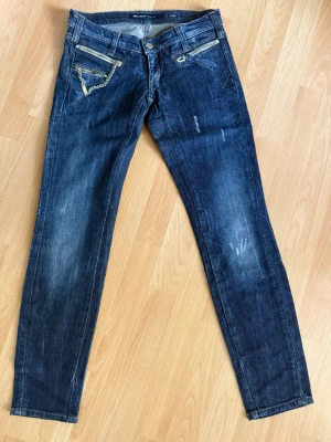  Miss sixty mörkblåa skinny jeans  - Snygga mörkblå skinny jeans från Miss Sixty med slitningar och cool kedjedetalj vid fickan. Jeansen har dragkedjor på fickorna fram och klassisk femficksdesign. Perfekta för dig som gillar en edgy och trendig stil.