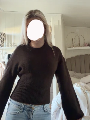 Mörkbrun croppad stickad tröja - Säljer en mörkbrun croppad stickad tröja med rund halsringning och bred ribbstickad midja. Tröjan har långa, lite vidare ärmar och är gjord i ett mjukt material som känns skönt mot huden. 