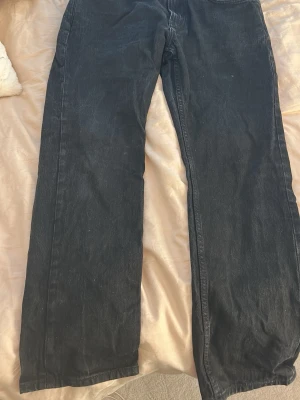 Svarta raka jeans från 157 - Säljer ett par svarta jeans från 157 med rak passform och klassisk femficksdesign. Jeansen har bälteshällor och stängs med knapp och dragkedja. 