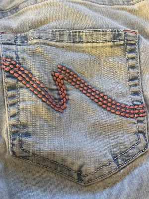 Ljusblå jeans från Nelly - Säljer ett par ljusblå jeans från Nelly med coola rosa detaljer på bakfickan. Jeansen har klassisk femficksdesign och är gjorda i denim. Perfekta för dig som vill ha en unik touch på din denimstil. 