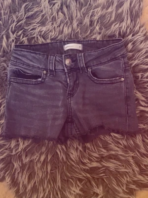 Grå low/normal waist shorts med knappdetalj - Säljer ett par snygga mörk gråa shorts i low till normal midja som är egengjorda
