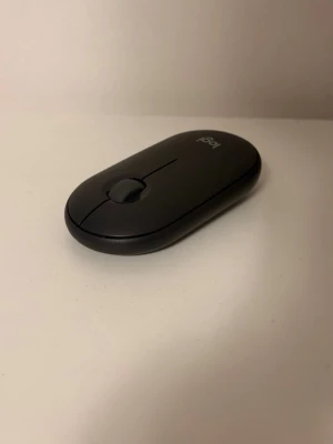 Logitech Pebble Mouse 2 M350s svart - Snygg och slimmad svart trådlös mus från Logitech, modell Pebble Mouse 2 M350s. Musen har en minimalistisk oval form och är tillverkad i plast. Passar perfekt till både laptop och stationär dator, ansluts via Bluetooth.