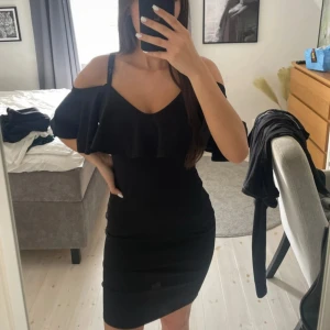 Svart klänning - Nelly storlek s. Svart klänning med volang både fram och bak. Klänningen har även justerbara band. Använd en gång. 