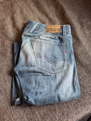 Ljusblå Replay jeans herr - Säljer ett par ljusblå jeans från Replay med klassisk femficksdesign och snygga slitningar. Jeansen har en patch bak i midjan och Replay-logga på fickan fram. Sköna och stilrena jeans i bomull, perfekta till en avslappnad look.