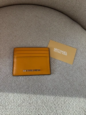 Michael Kors Korthållare / Plånbok  - Snygg Michael Kors korthållare / plånbok. I fin senapsgul solgul färg. Som ny och endast använd ett fåtal gånger. Med ett fack på baksidan, mitten och tre på framsidan. 