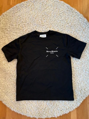 Svart Maison Margiela t-shirt - Säljer en svart t-shirt från Maison Margiela med tryck på både bröstet och ryggen. Klassiks passform.