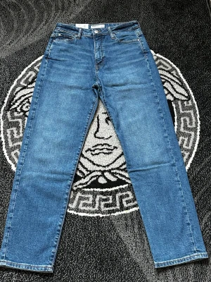 Blå raka jeans från Weekday - Säljer ett par klassiska blå jeans från Weekday med rak passform och hög midja. Jeansen har fem fickor, dragkedjegylf och är gjorda i ett slitstarkt denimtyg. Perfekta till en avslappnad och trendig look.