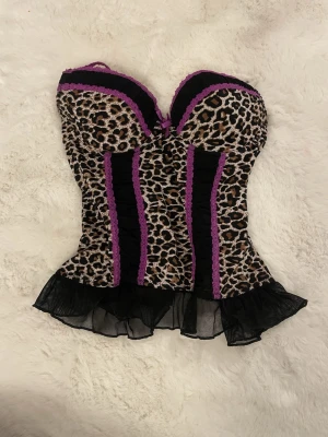 Den e såld! - ❗️NÄSTAN ALDRIG ANVÄND❗️Supersnygg korsett-tröja i leopardmönster med svarta partier och lila spetsdetaljer 💜 Formar fint, sitter tajt och ger en riktigt cool Y2K/party-look. Perfekt till fest, utekväll eller stylad med jeans för en edgy outfit.