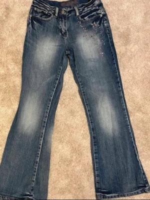 Lågmidjade bootcut jeans - Ursnygga lågmidjade vintage jeans! Super fina små rosa detaljer vid sidan, säljer pga att de inte passar mig så bra💕storleken är för barn 12 och 152cm
