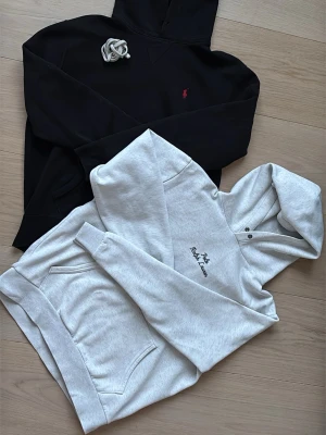 Grå och svart hoodie från Polo Ralph Lauren - Säljer en svart och en ljusgrå hoodie från Polo Ralph Lauren med broderad logga på bröstet. Hoodien har stor huva med knappar, magficka och ribbade muddar. Perfekt för en chill och avslappnad stil. Materialet är mjukt och skönt bomullstyg. Dom har blivit försmå för mig de är storlek M. 1099 kr för båda 559 för bara en😁